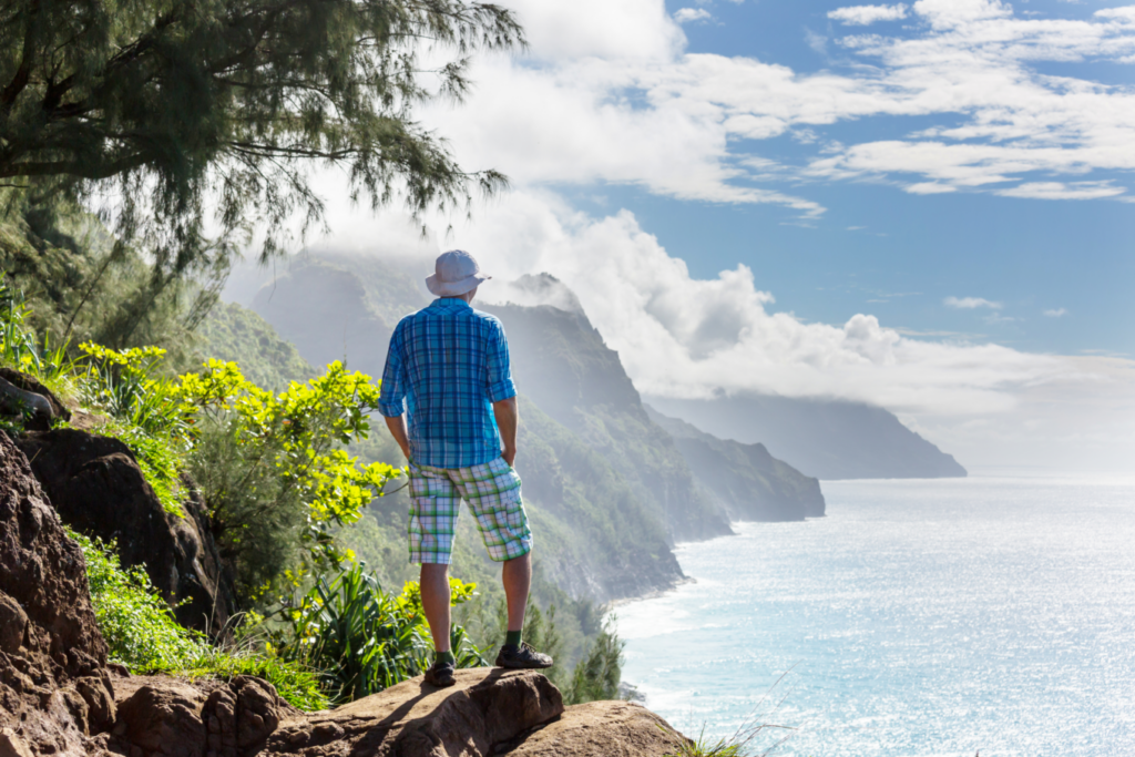 A man on a hike looking out at the coastline of Hawaii